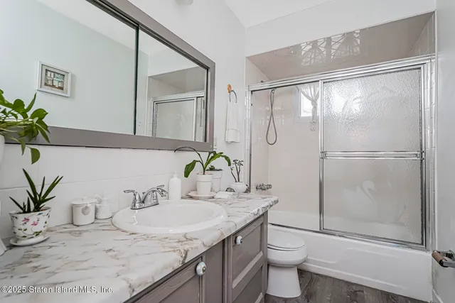 a bathroom with a granite countertop sink a toilet and shower