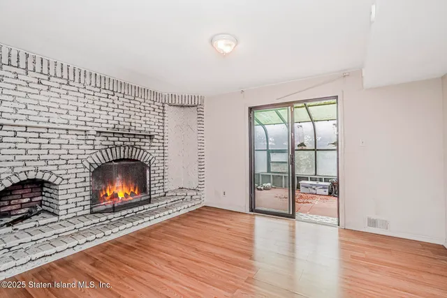 an empty room with wooden floor fireplace and windows