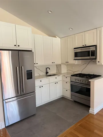 a kitchen with stainless steel appliances wooden floor and large window