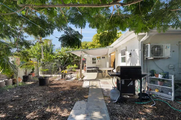 a view of a patio with table and chairs potted plants and large tree