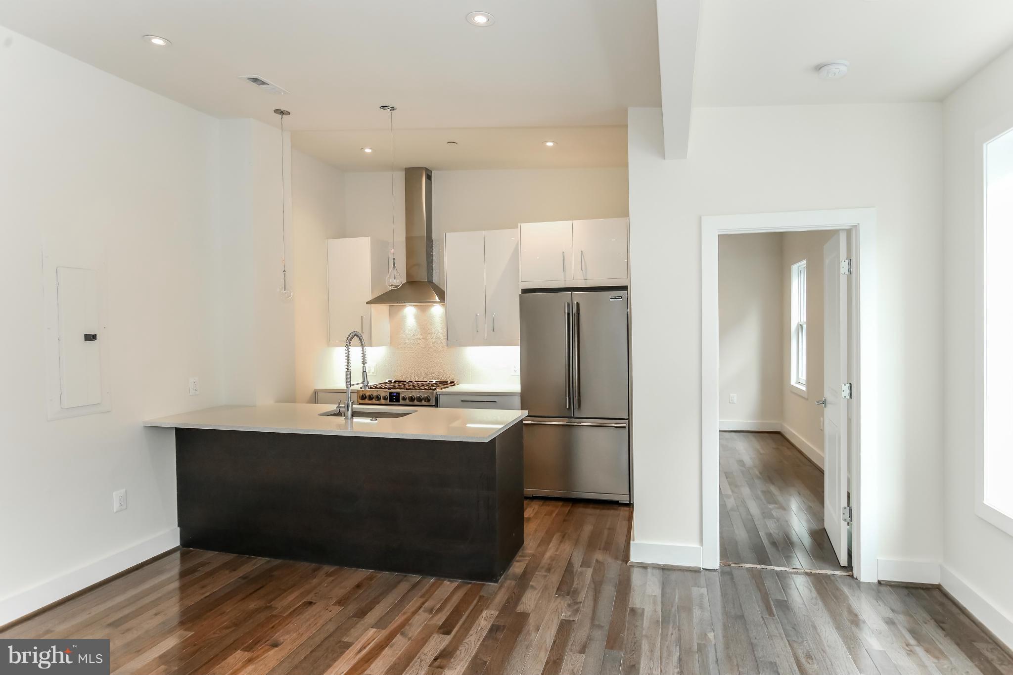 462 Ridge Street Northwest, Unit 3 Washington, DC 20001 - Photo 8 of 20 a kitchen with stainless steel appliances a refrigerator and wooden floor