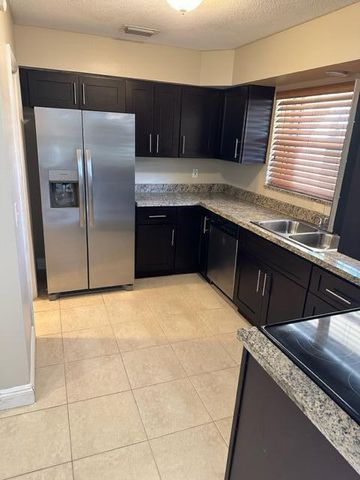 a kitchen with stainless steel appliances granite countertop a sink and a refrigerator