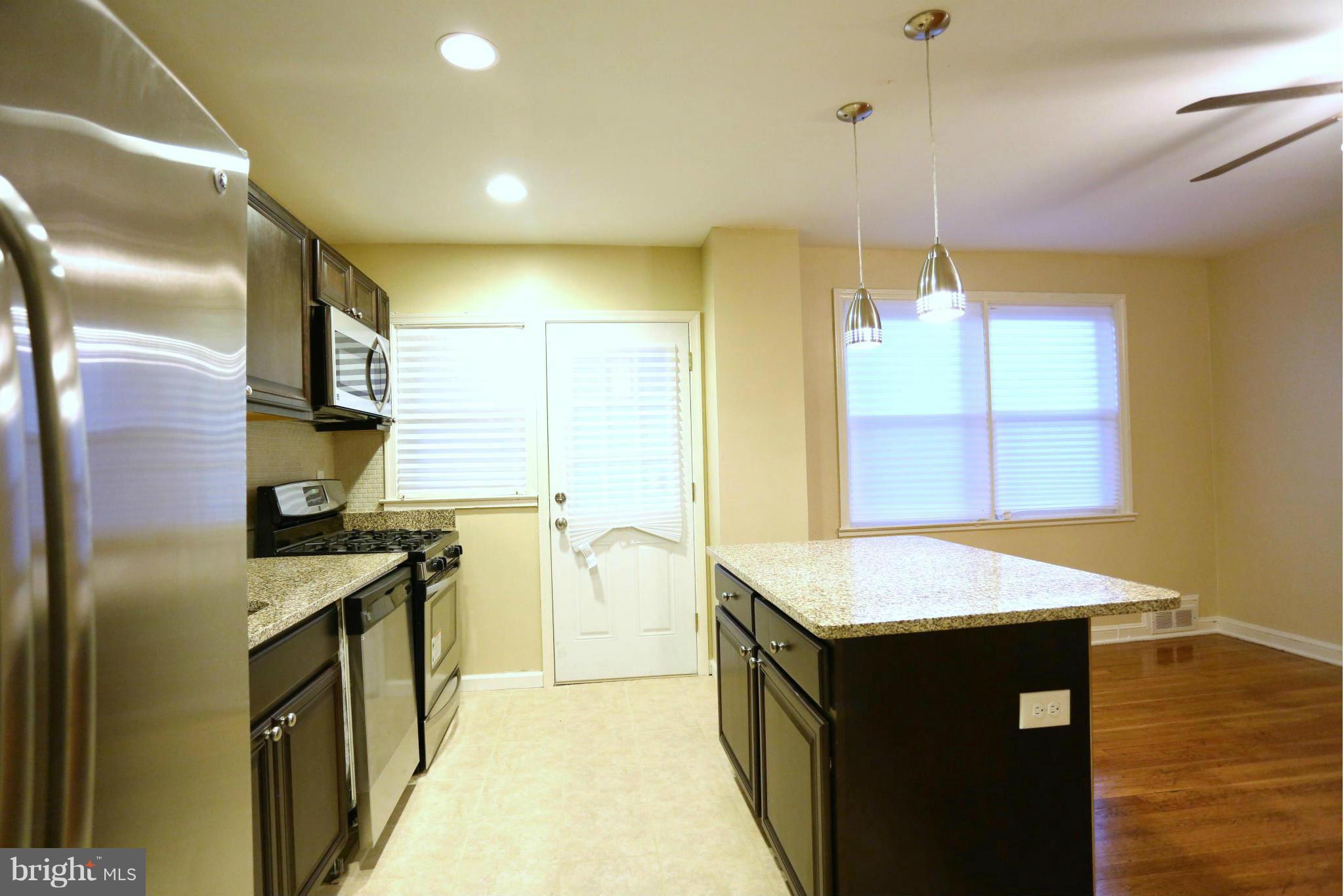 5222 Kelway Road Baltimore, MD 21239 - Photo 3 of 25 a kitchen with stainless steel appliances granite countertop a sink a stove and a wooden floors