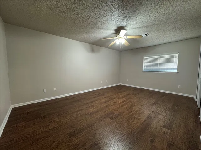 an empty room with wooden floor chandelier fan and windows
