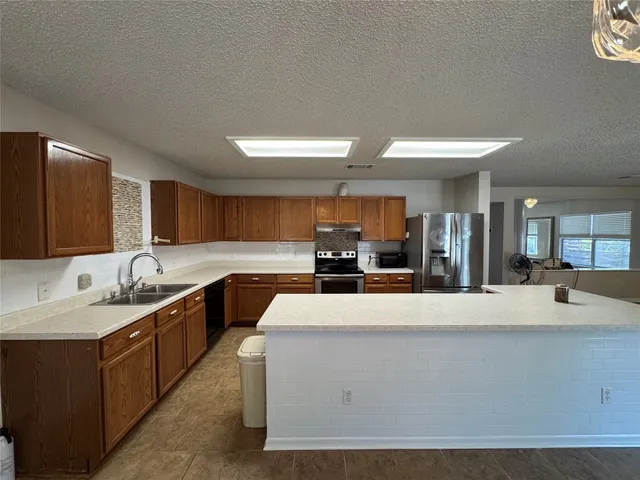 a large white kitchen with kitchen island a sink a stove and a refrigerator with wooden floor