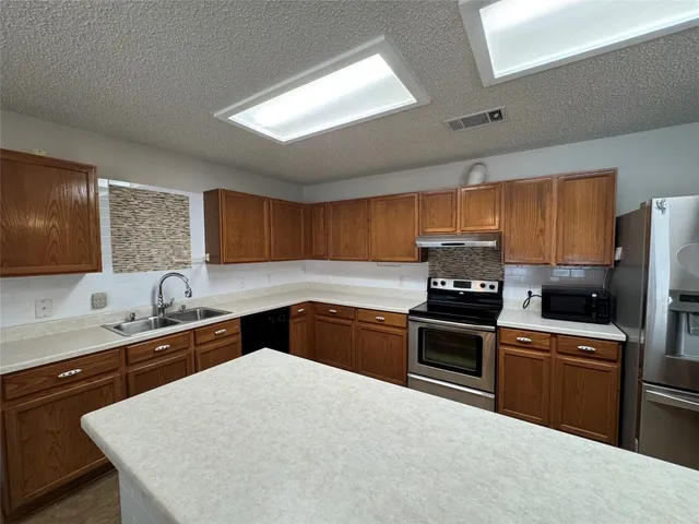 a kitchen with granite countertop a sink stove and refrigerator