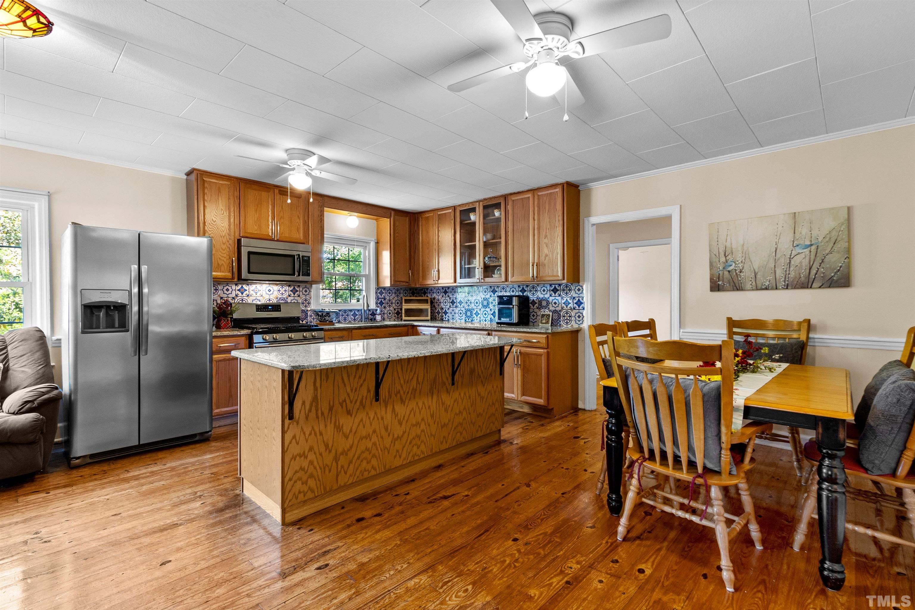5100 Clearview Street Raleigh, NC 27603 - Photo 23 of 36 a kitchen with stainless steel appliances granite countertop a refrigerator a stove a sink a dining table and chairs with wooden floor