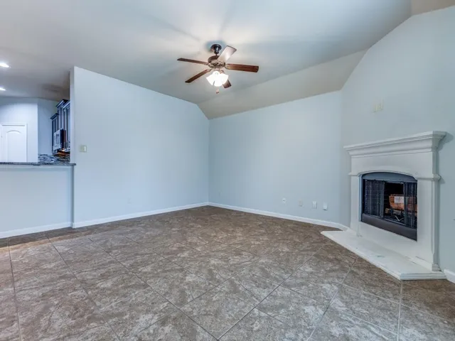 a view of an empty room with a fireplace and a chandelier fan