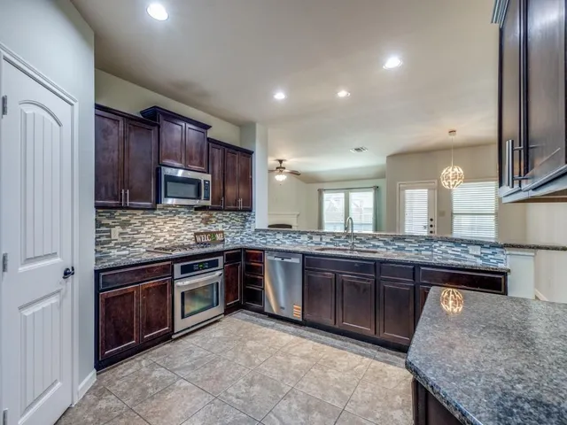 a kitchen with kitchen island granite countertop wooden cabinets and a stove top oven