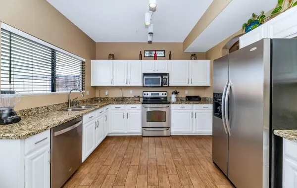a kitchen with granite countertop a stove a sink a dining table and chairs