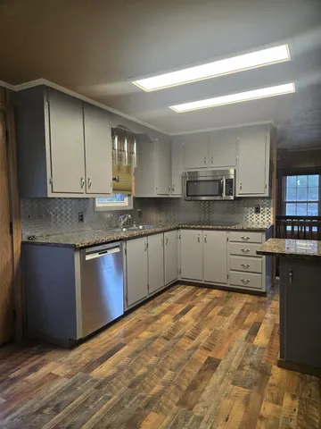 a kitchen with granite countertop a sink cabinets and stainless steel appliances