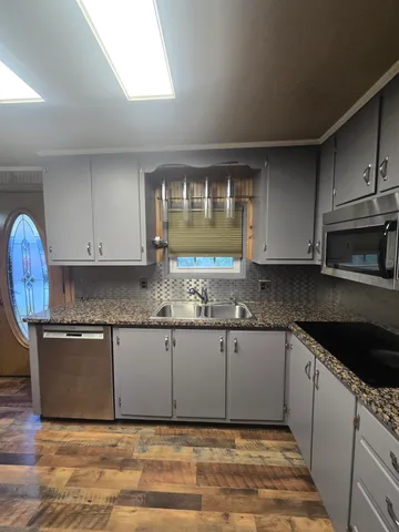 a kitchen with granite countertop a sink cabinets and wooden floor