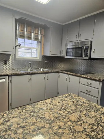 a kitchen with granite countertop a sink and cabinets