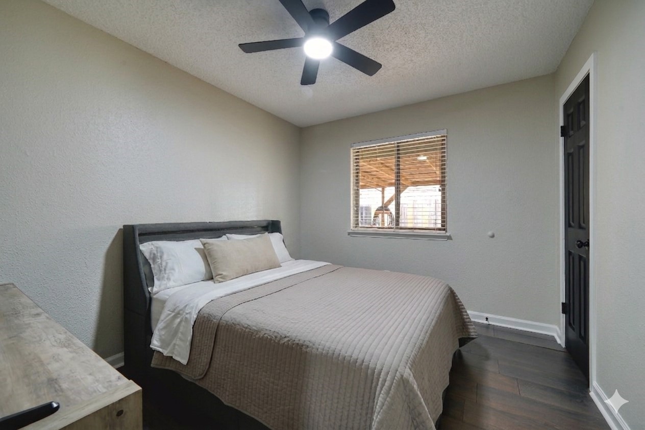 5402 Sherrylee Lane Spring, TX 77373 - Photo 12 of 21 Bright, inviting bedroom featuring neutral walls, wood-style flooring, and a window that brings in natural light, complemented by a sleek modern ceiling fan.