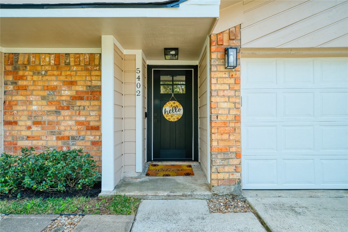5402 Sherrylee Lane Spring, TX 77373 - Photo 3 of 24 The inviting front entry is highlighted by a stylish black door, framed by classic brick and siding accents. The well-lit porch and tidy landscaping enhance the home’s welcoming curb appeal, with the garage conveniently positioned nearby.
