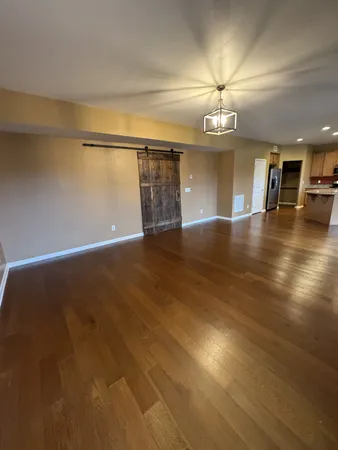 an empty room with wooden floor chandelier and windows