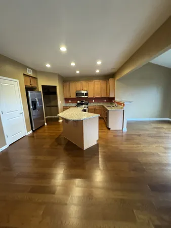 a living room with stainless steel appliances furniture a rug and a kitchen view