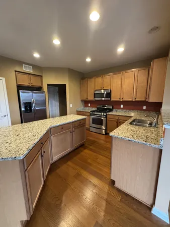 a large kitchen with stainless steel appliances granite countertop a large counter top a stove a sink and a refrigerator