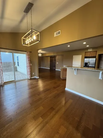 a view of a room with wooden floor and kitchen view