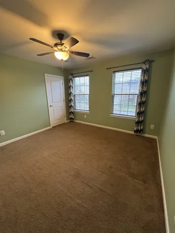 an empty room with windows and ceiling fan