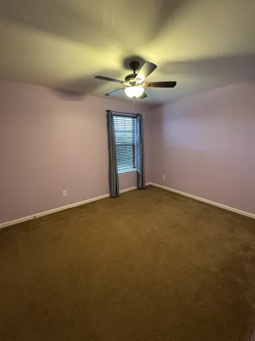 an empty room with a window and a ceiling fan