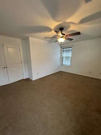 an empty room with windows and ceiling fan