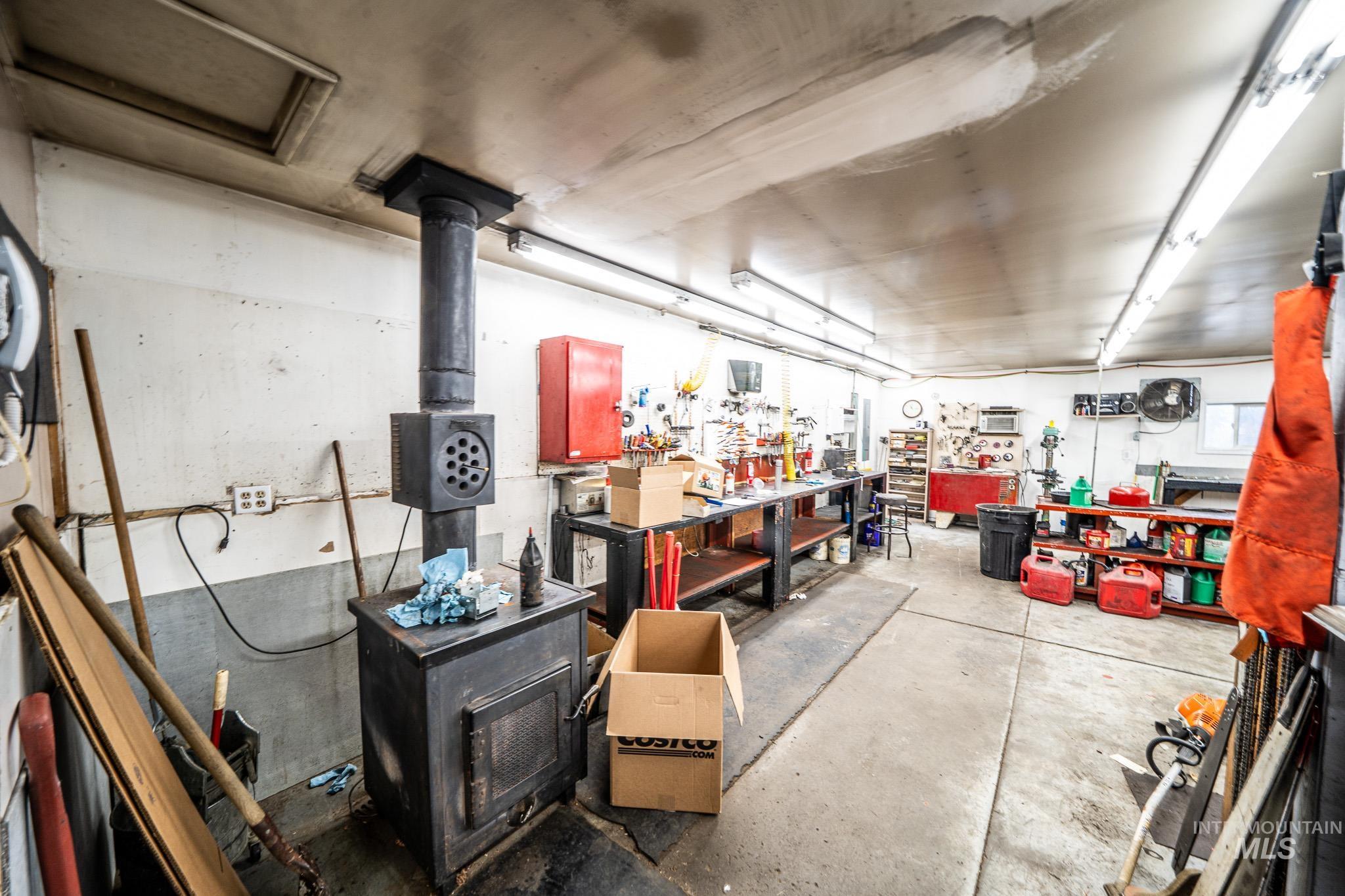 10 Main Street South Pierce, ID 83546 - Photo 14 of 27 Miscellaneous room featuring concrete flooring, a wood stove, and a workshop area