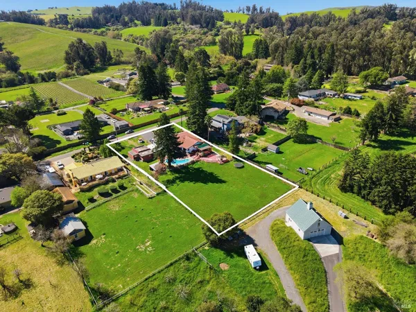 an aerial view of a house with swimming pool a yard and lake view