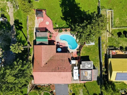an aerial view of a tennis ground and a cars park side of the road