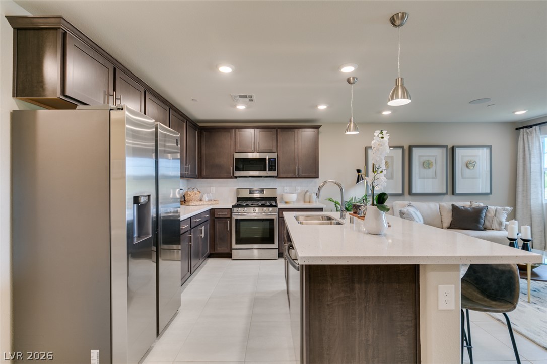 653 Pickled Pepper Place Henderson, NV 89011 - Photo 16 of 35 A contemporary kitchen features rich cabinetry, stainless steel appliances, and a central island with pendant lighting.