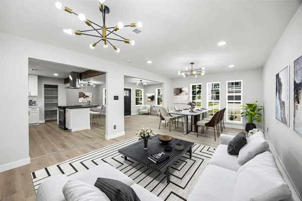 a living room with furniture kitchen view and a chandelier