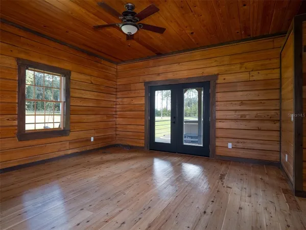 a view of empty room with wooden floor and fan