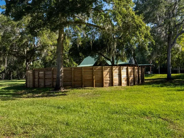 a view of a backyard with large trees and wooden fence