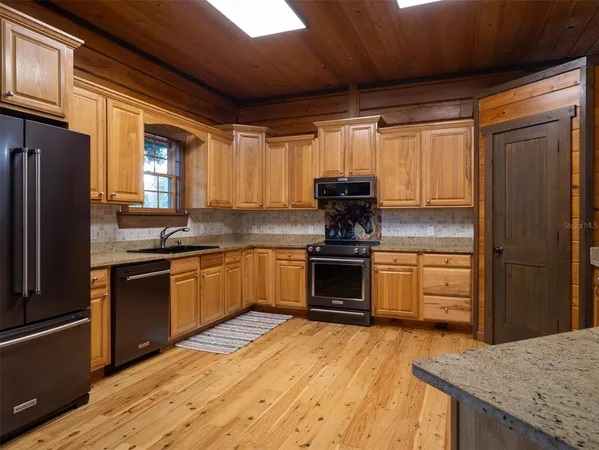 a kitchen with granite countertop a refrigerator stove and sink