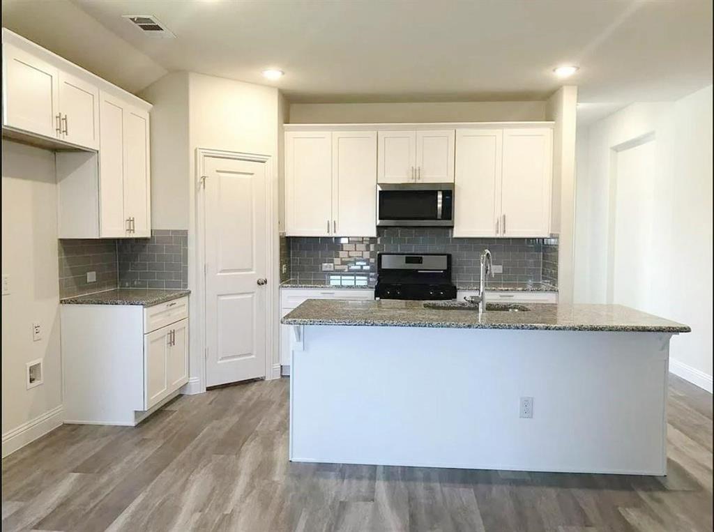 3817 Bennett Trail Celina, TX 75009 - Photo 5 of 22 a kitchen with stainless steel appliances a stove top oven a sink a refrigerator white cabinets and wooden floor