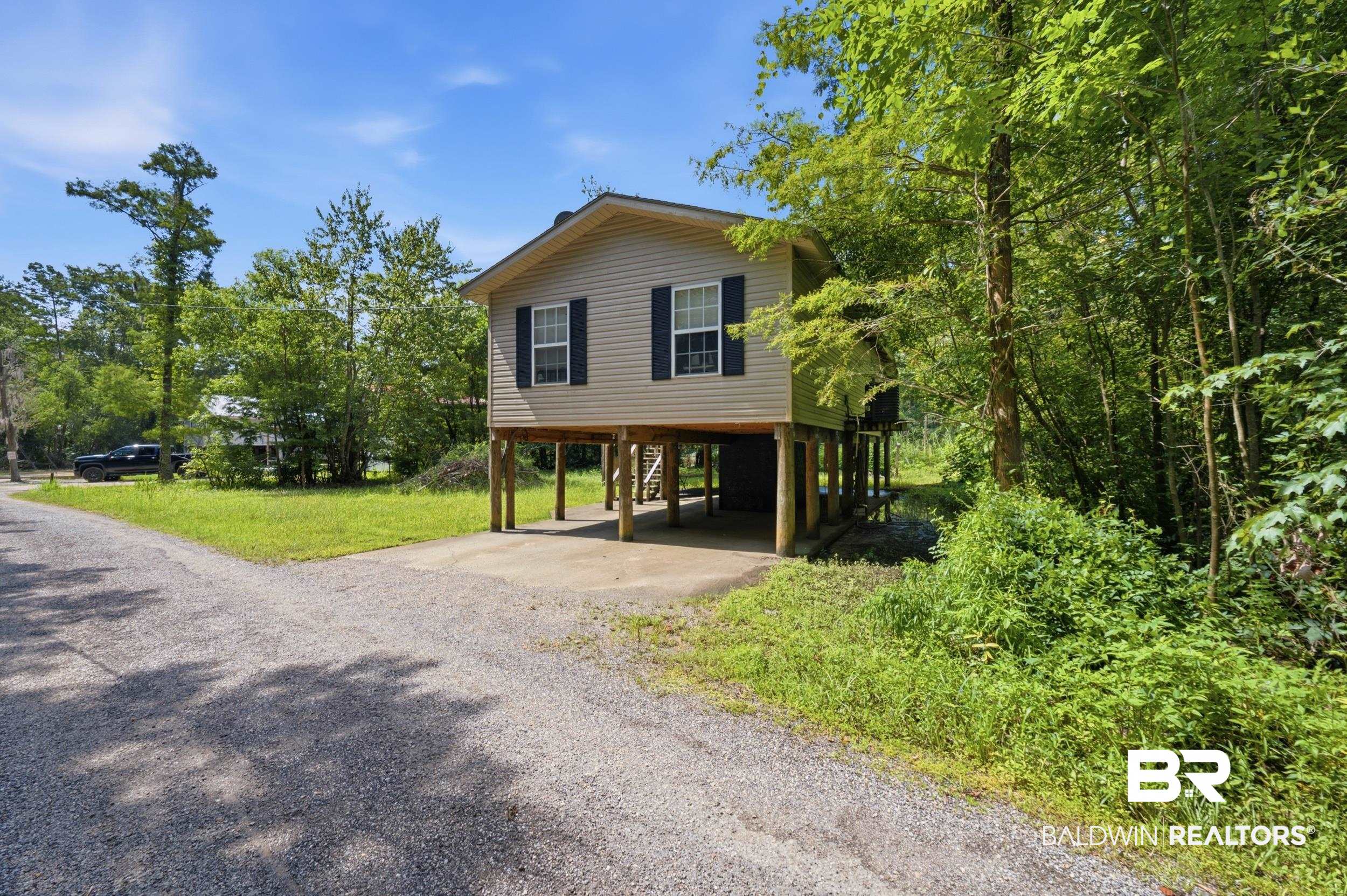 42080 Bayou Road Bay Minette, AL 36507 - Photo 3 of 43 Elevated home featuring light-toned siding, dark window shutters, and a metal roof