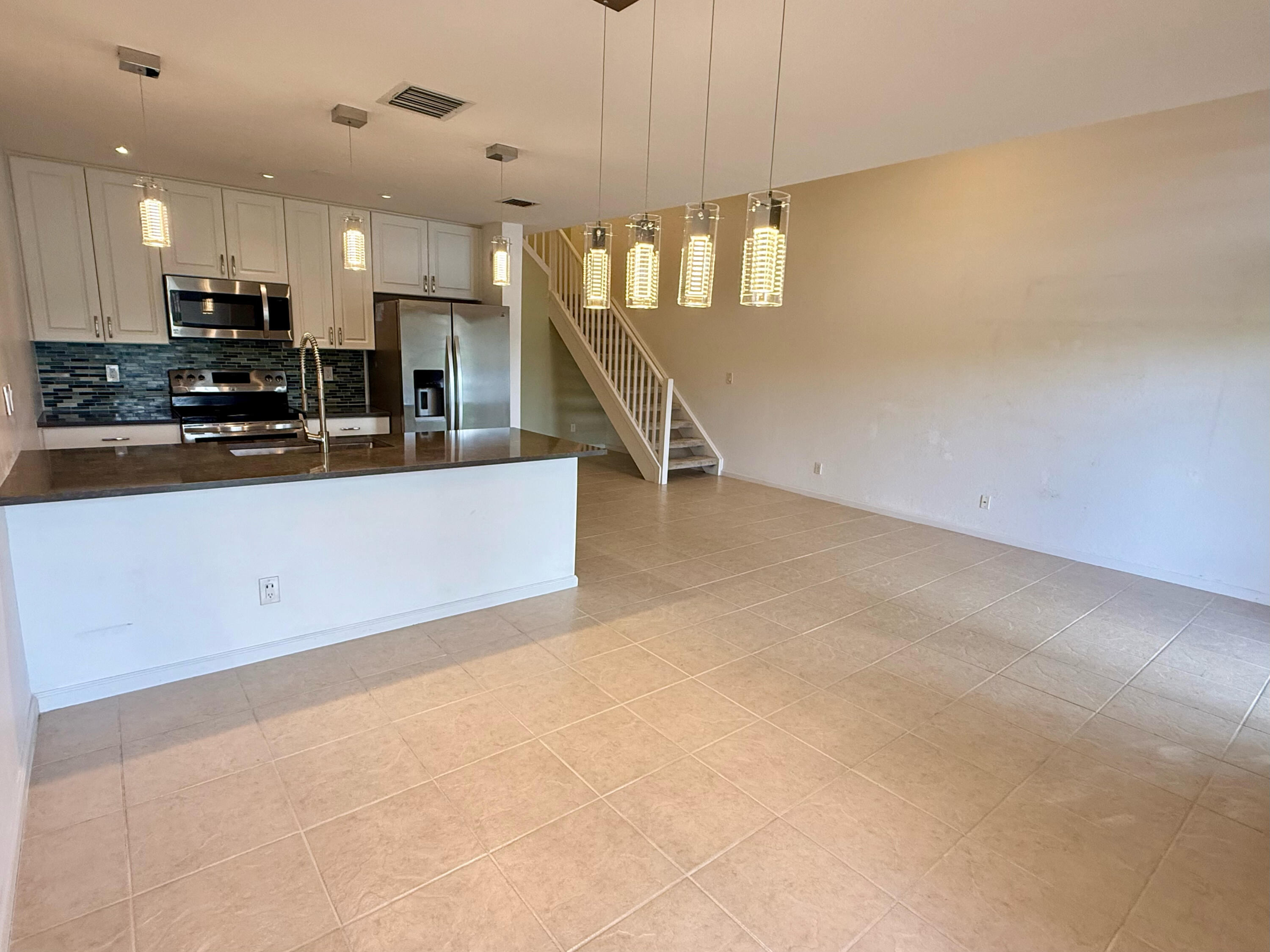 12813 Woodmill Drive Palm Beach Gardens, FL 33418 - Photo 5 of 30 a view of a kitchen with kitchen island a sink wooden floor and stainless steel appliances