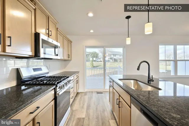 a kitchen with granite countertop a sink a stove and cabinets