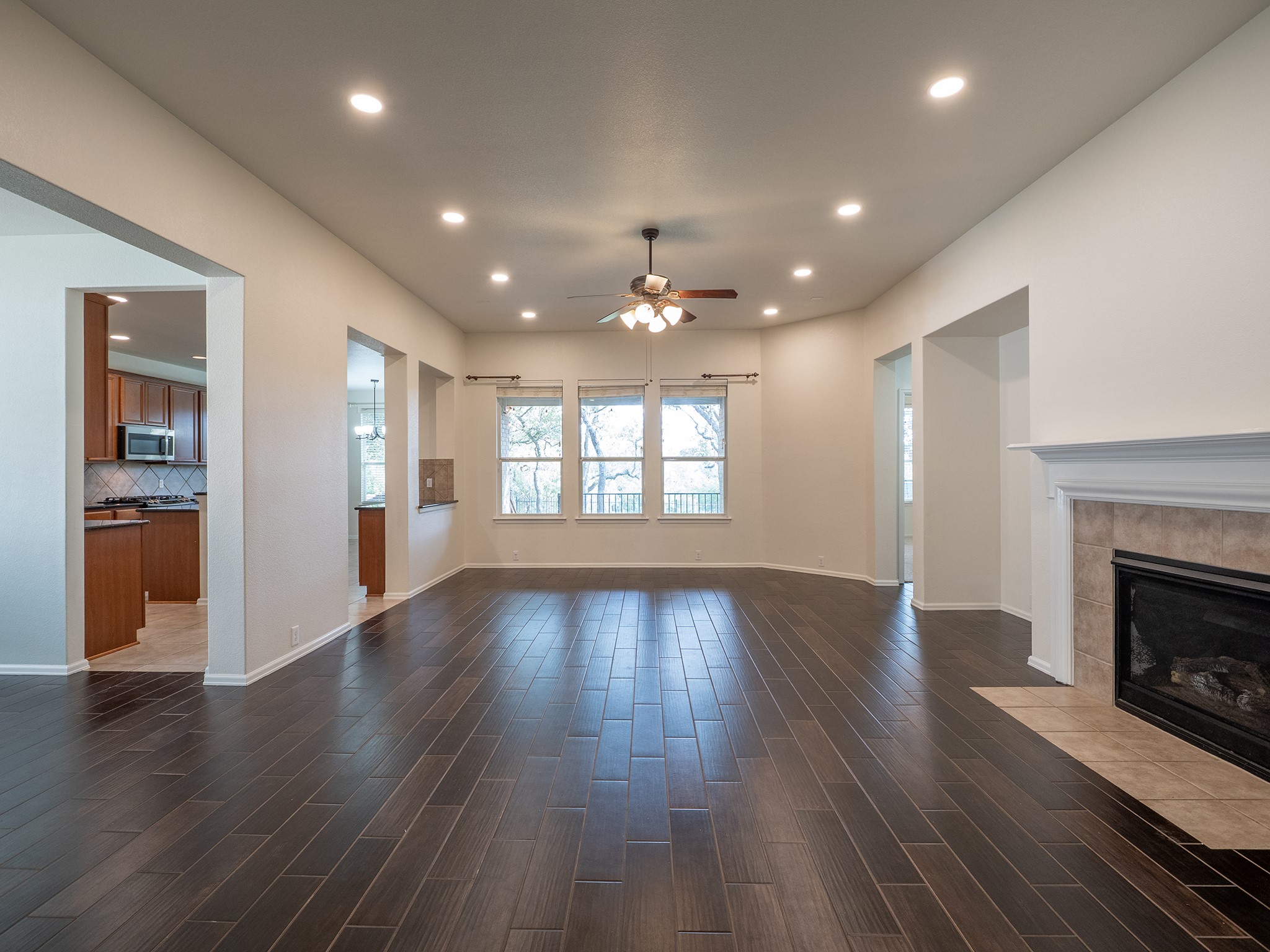 572 Big Meadow Road Austin, TX 78737 - Photo 11 of 32 Rich wood plank flooring flows throughout this generous living area, complemented by a tiled fireplace and ample natural light.