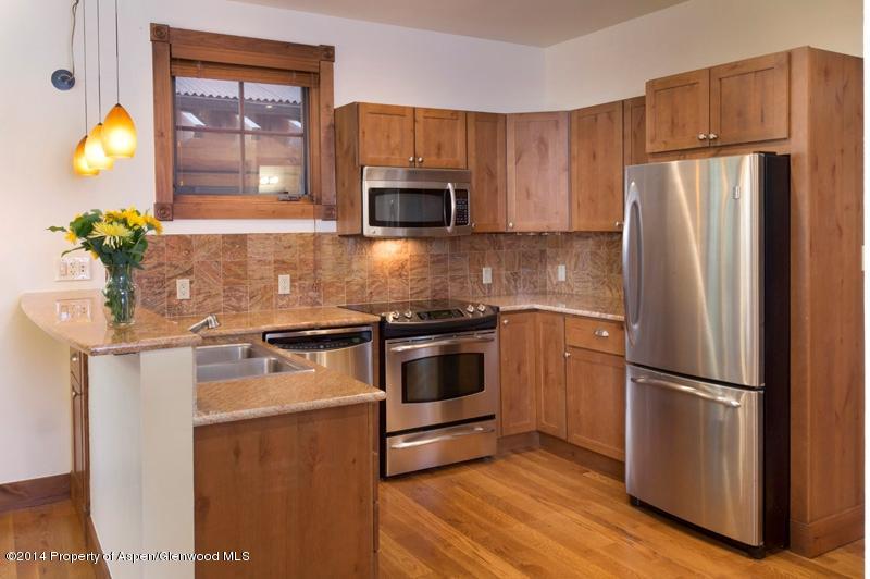 507 West Main Street, Unit C101 Aspen, CO 81611 - Photo 3 of 16 a kitchen with granite countertop stainless steel appliances and wooden cabinets