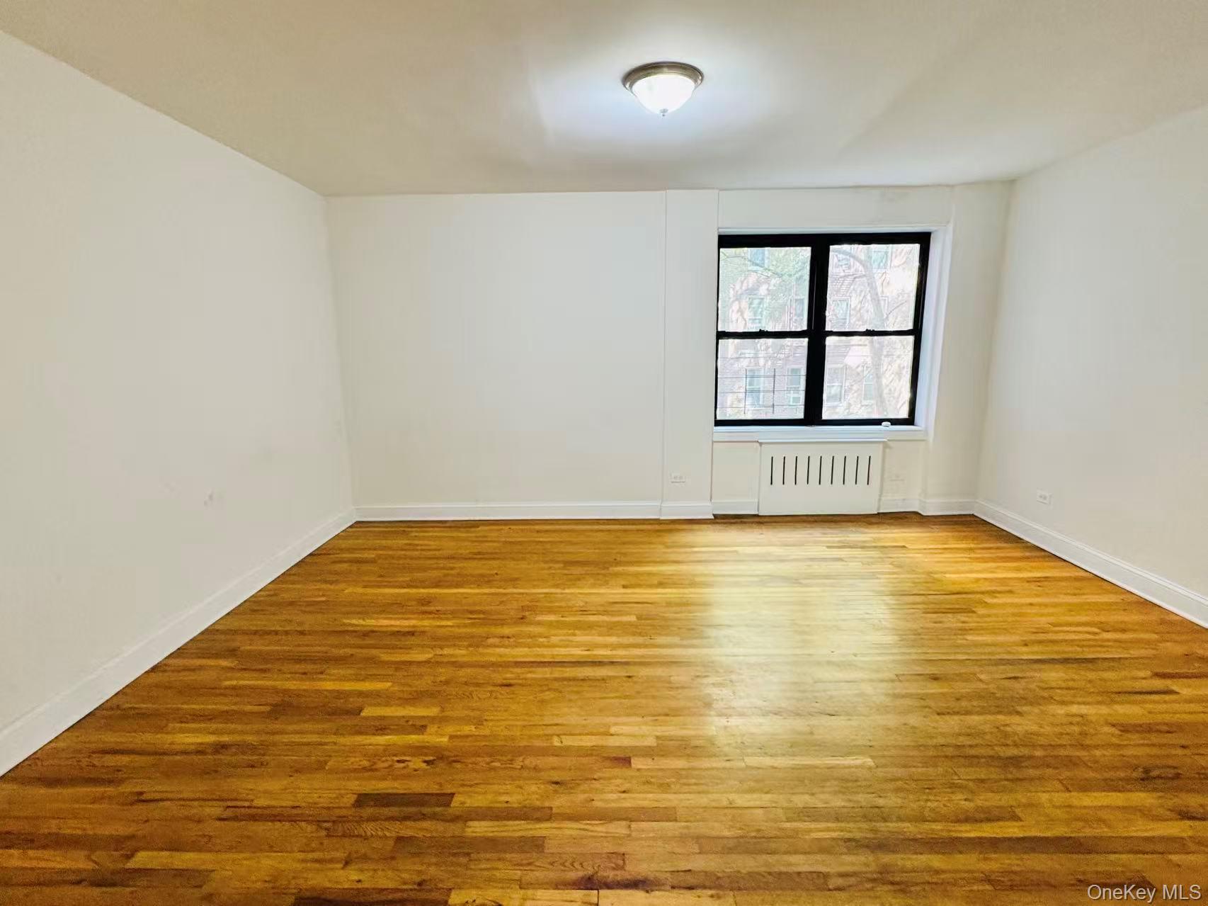 44-05 Macnish Street, Unit 2G Queens, NY 11373 - Photo 7 of 12 Unfurnished room featuring light wood-style flooring and radiator heating unit