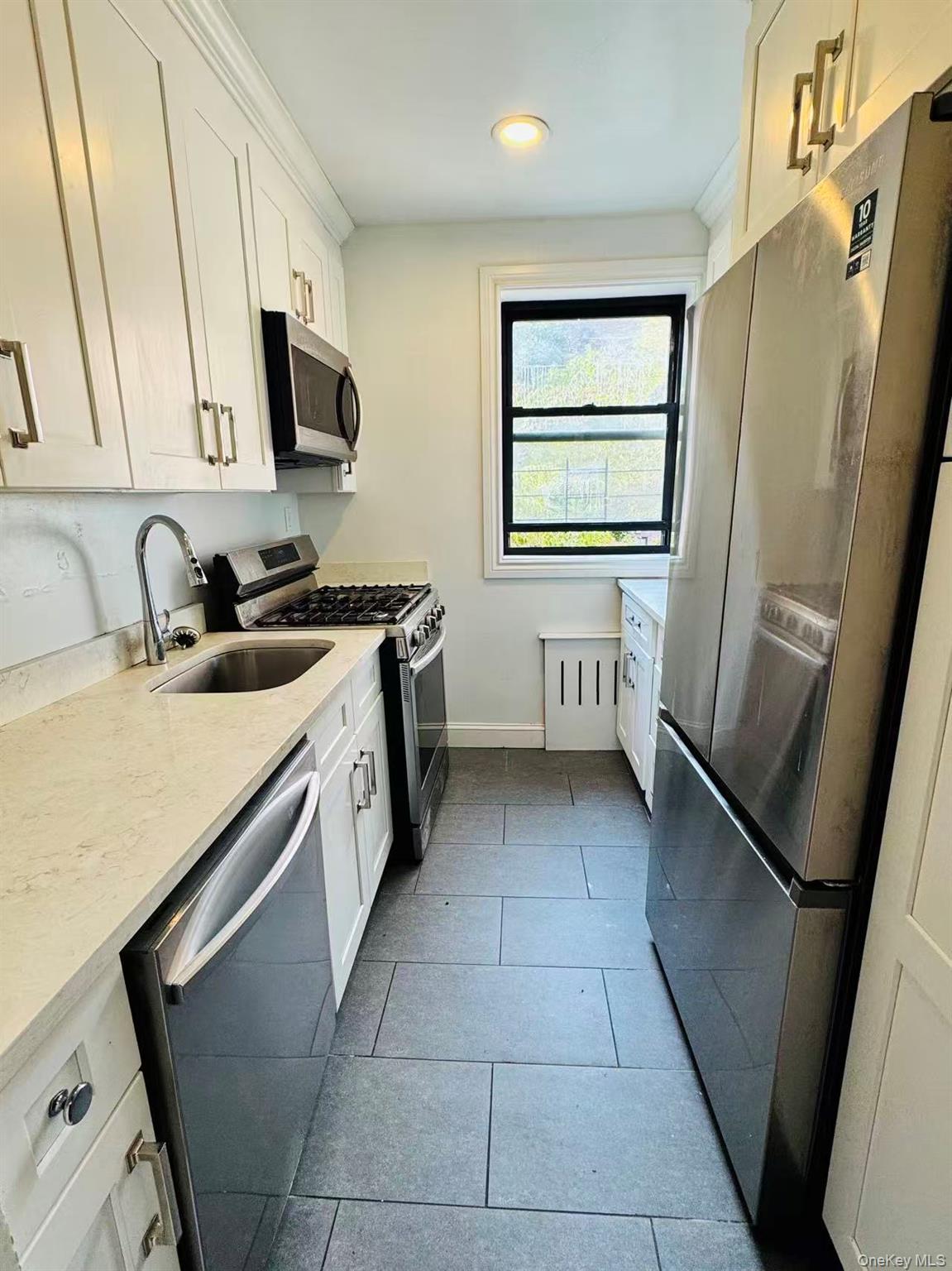 44-05 Macnish Street, Unit 2G Queens, NY 11373 - Photo 8 of 12 Kitchen featuring stainless steel appliances, white cabinetry, light stone counters, light tile patterned floors, and recessed lighting