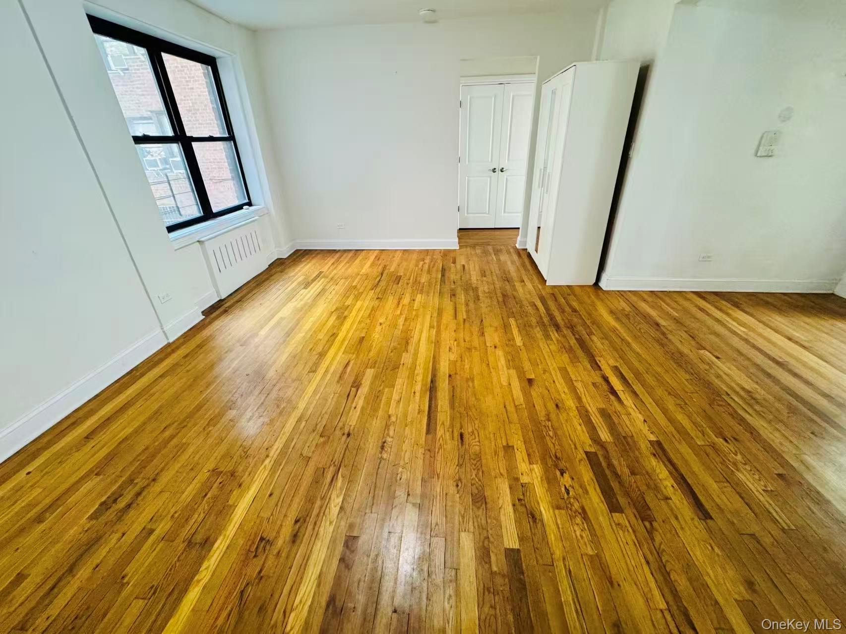 44-05 Macnish Street, Unit 2G Queens, NY 11373 - Photo 10 of 12 Unfurnished room featuring light wood-style flooring and radiator heating unit
