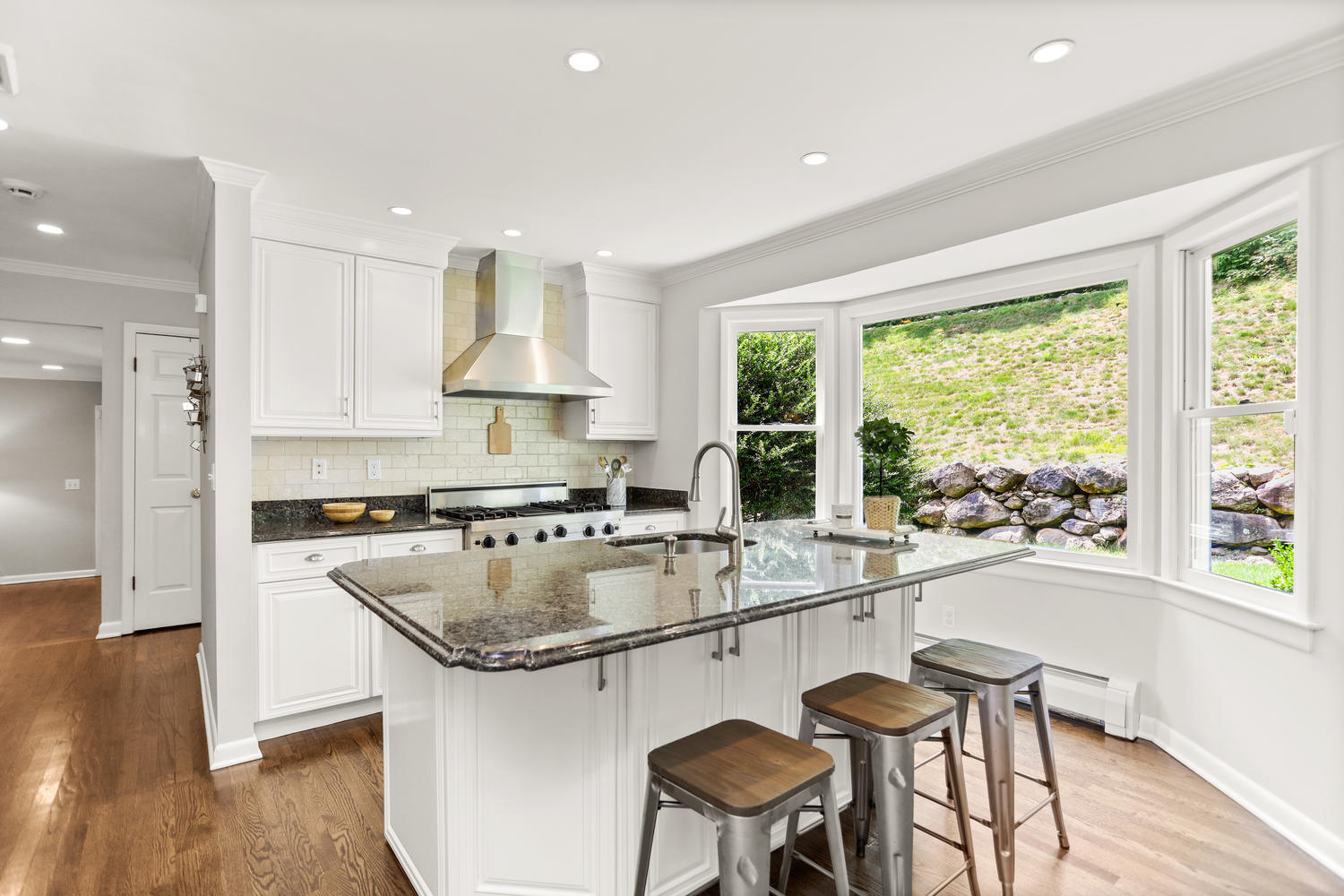 704 Valley Road New Canaan, CT 06840 - Photo 21 of 59 a kitchen with a stove a sink a refrigerator and white cabinets with wooden floor