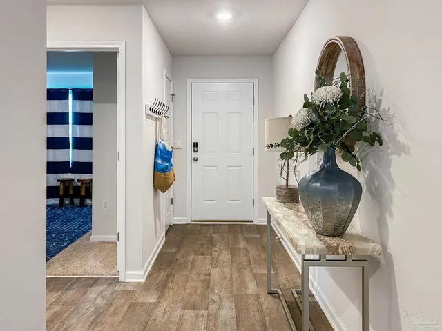 a view of a hallway with wooden floor and a potted plant