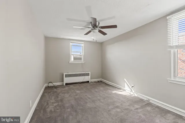 an empty room with windows and fan