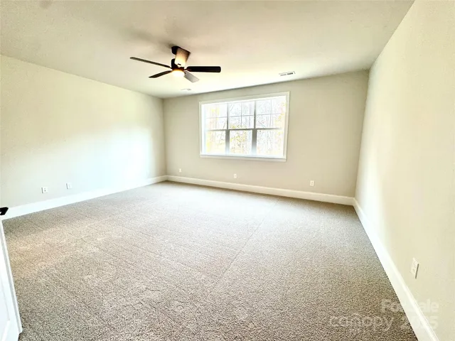 an empty room with a ceiling fan and window