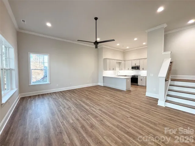 a view of a room with wooden floor staircase and a kitchen