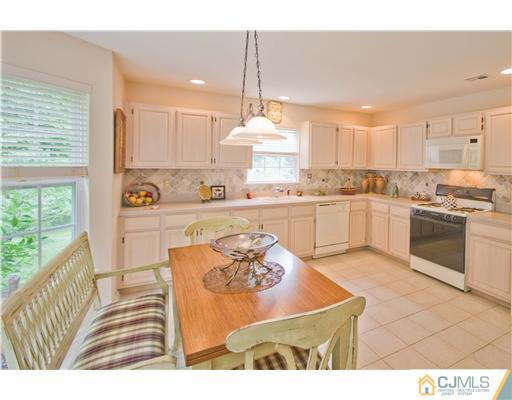 12 Stewart Court Old Bridge, NJ 08857 - Photo 11 of 14 a kitchen with stainless steel appliances granite countertop a stove a sink a refrigerator white cabinets with a dining table and chairs