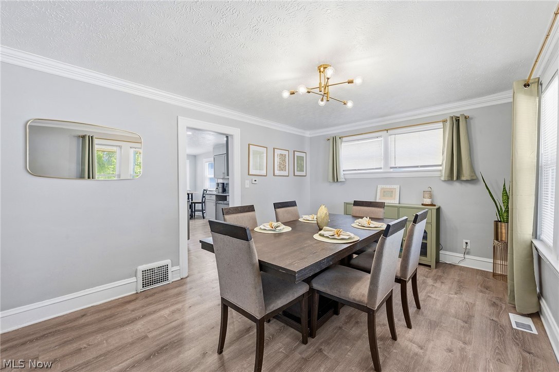3386 Sylvanhurst Road Cleveland Heights, OH 44112 - Photo 10 of 46 Dining area featuring wood-finish flooring, a contemporary ceiling light fixture, crown molding, and an open doorway to an additional space